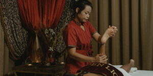 Eine thailändische Masseurin massiert konzentriert Unterschenkel und Füße einer Frau.