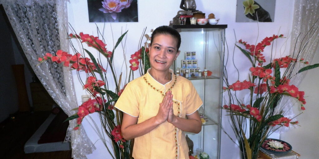 Kitty Kammer mit gefalteten Händen bei einer thailändischen Begrüßung ihrer Massagekunden.